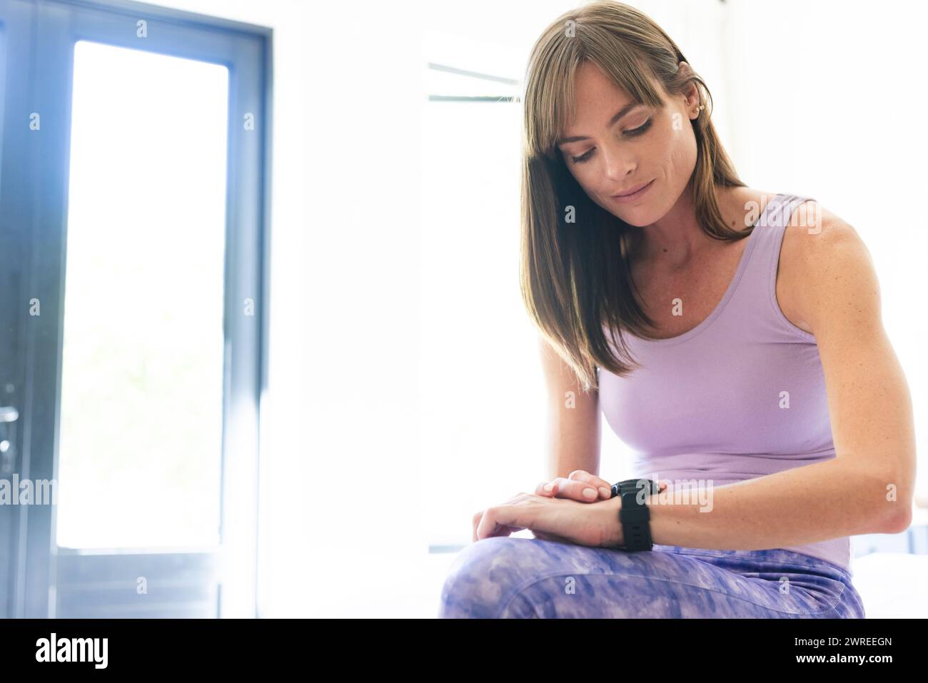 Caucasian woman with light brown hair checks her fitness tracker with copy space Stock Photo