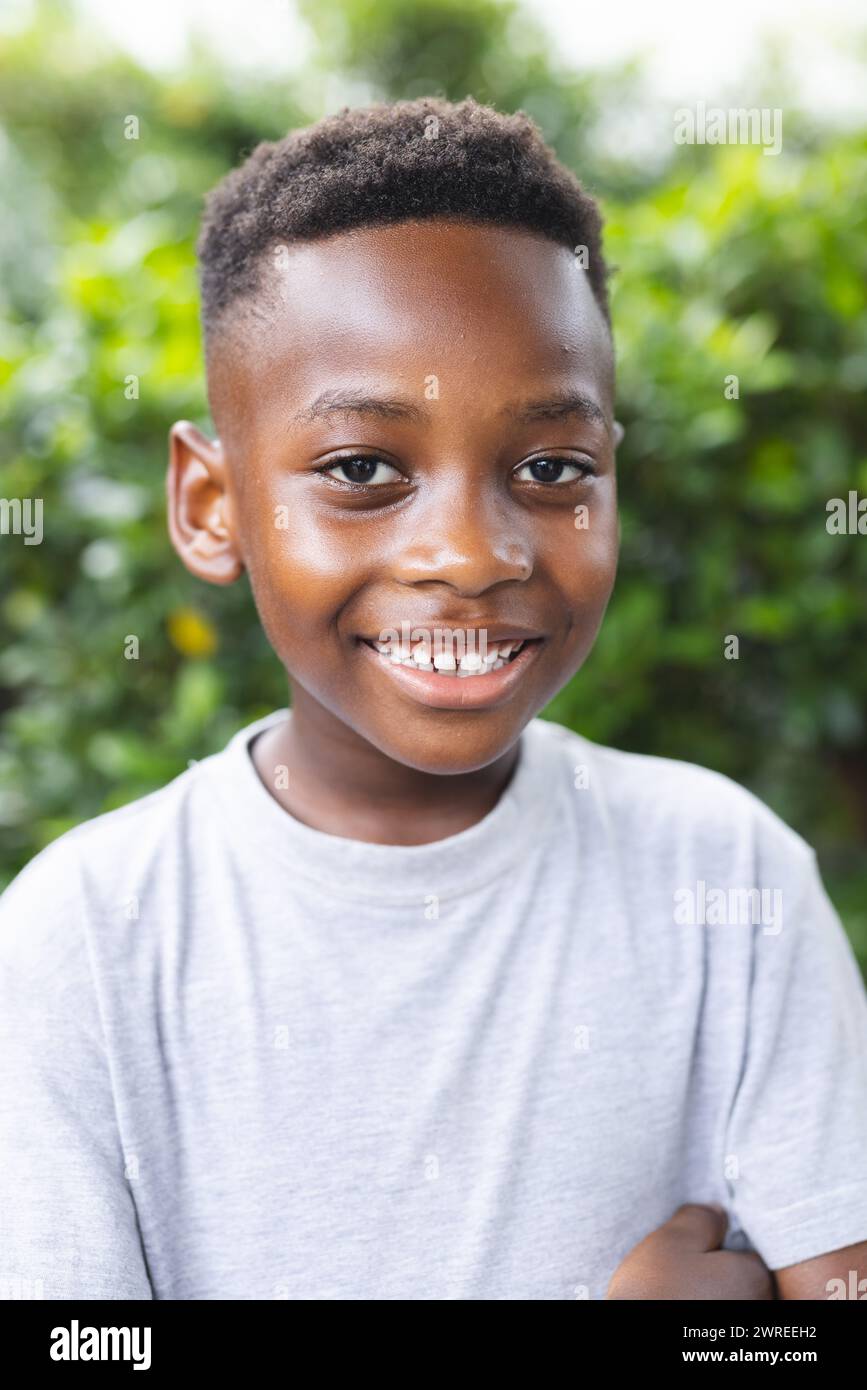 African American boy with a bright smile stands outdoors in a garden ...