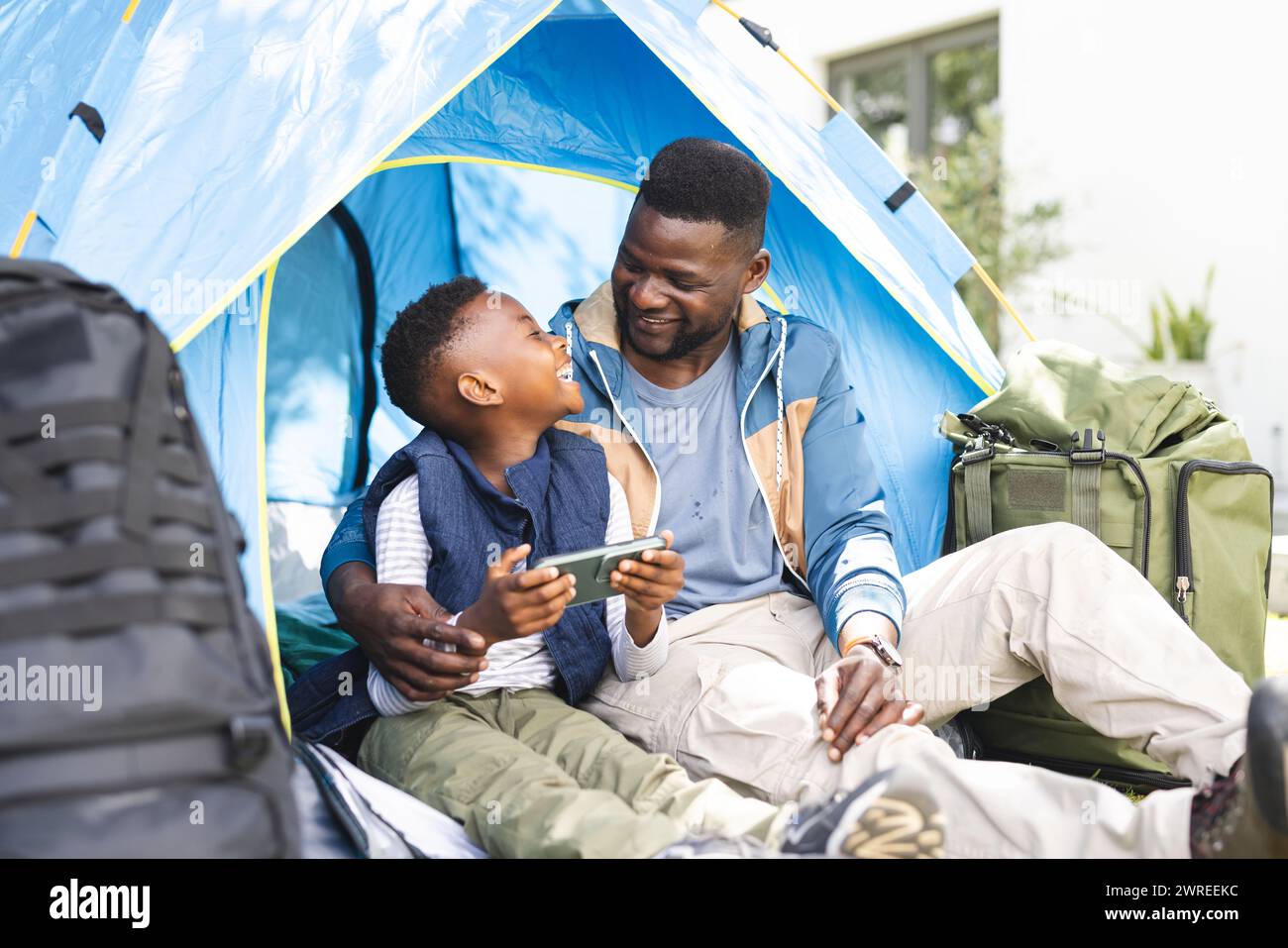 African American father and son share a joyful moment inside a tent in the backyard Stock Photo