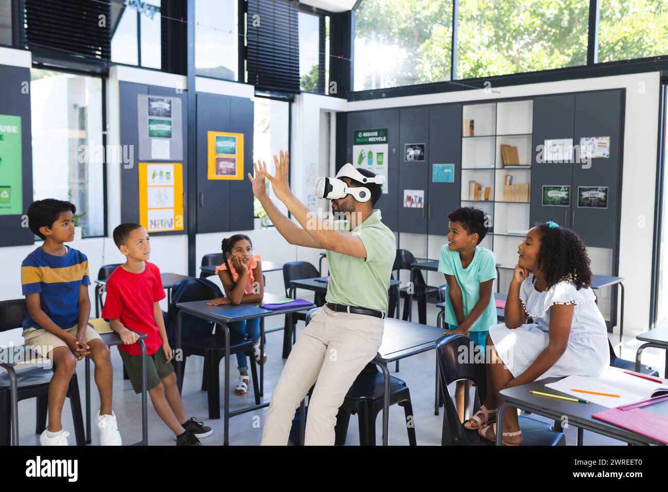 Young Asian male teacher is teaching a diverse group of children in a classroom setting in school Stock Photo