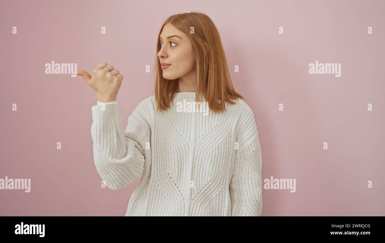 A young adult woman gestures to the side against an isolated pink background, exuding beauty and confidence. Stock Photo