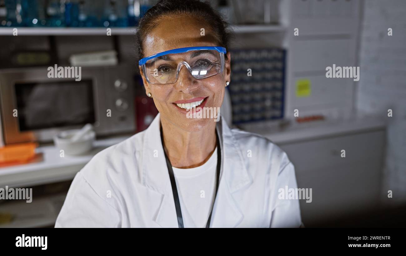 Smiling hispanic senior woman with curly hair wearing safety goggles in ...