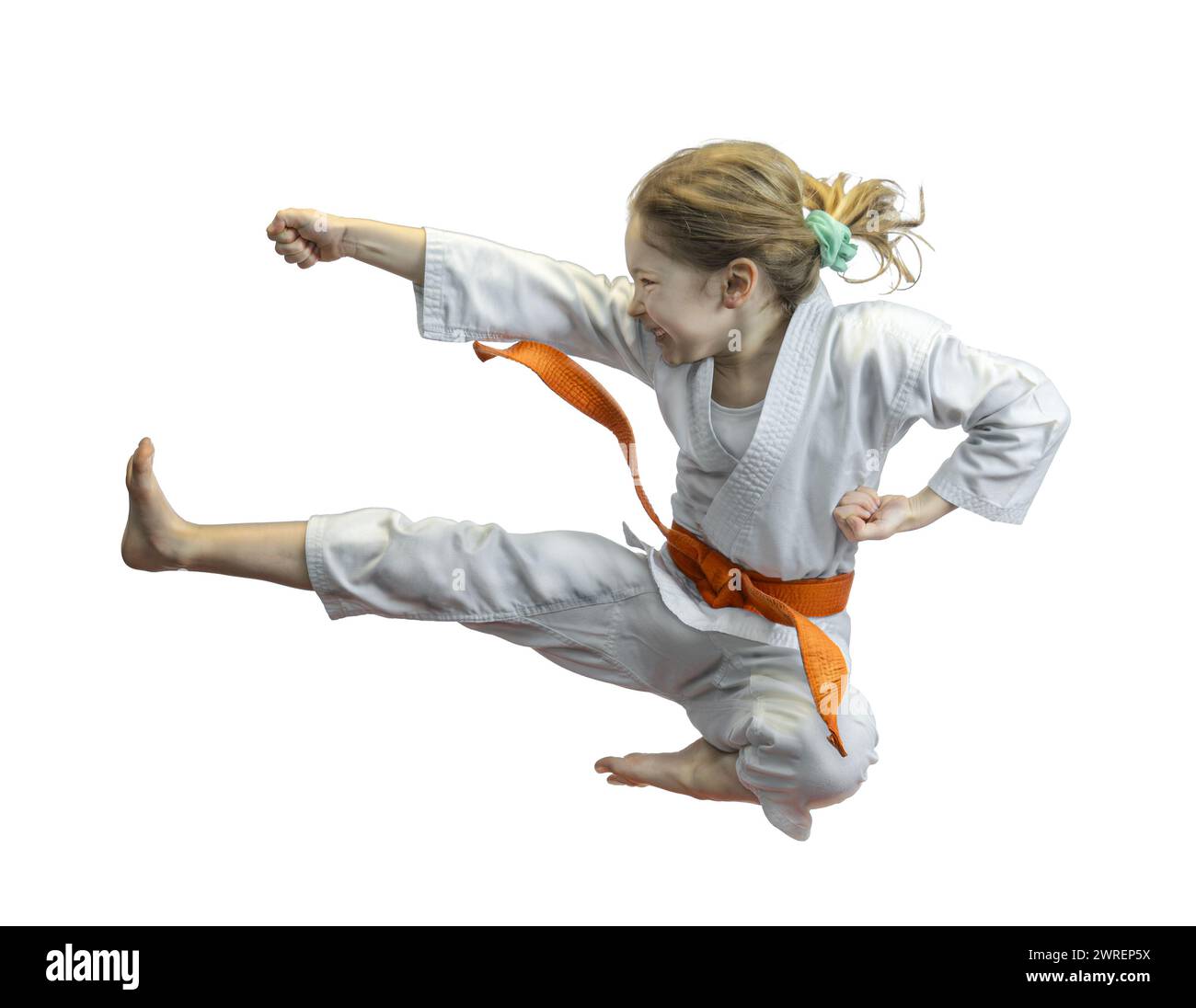 Energetic young girl in a karate uniform performing a high kick Stock Photo