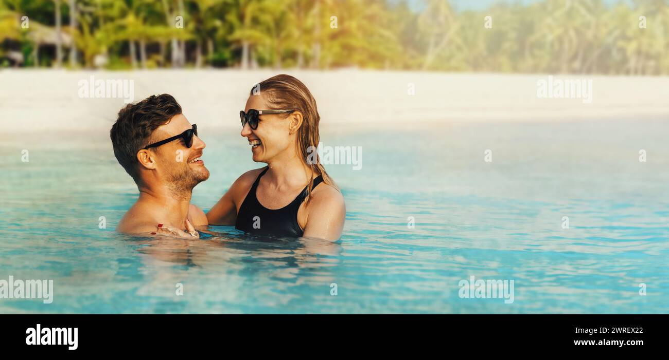 happy couple in love swimming in the ocean by tropical white sand beach. romantic getaway. banner with copy space Stock Photo