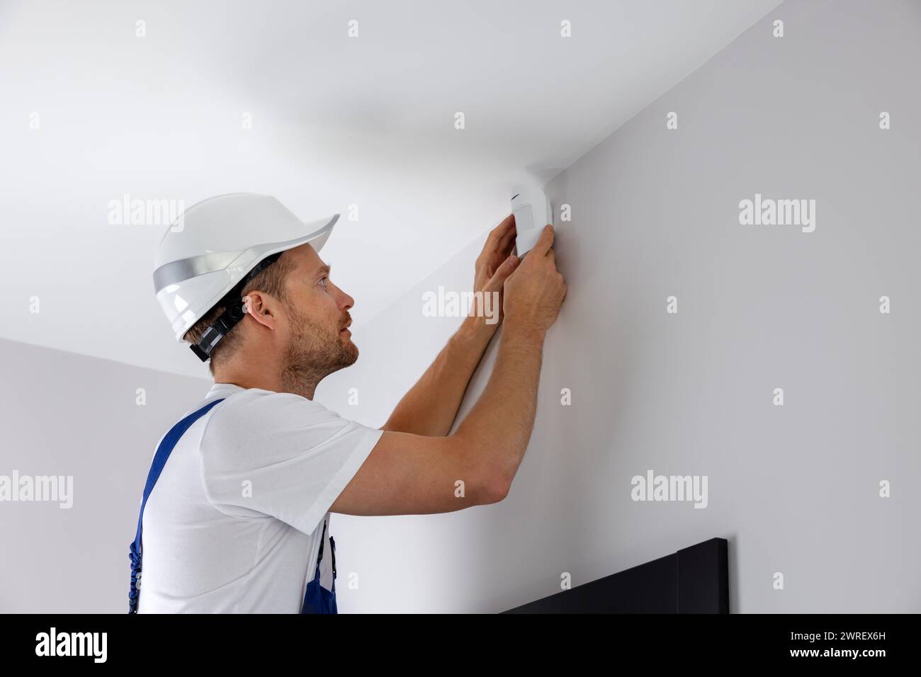 security system technician installing motion sensor on the wall at home Stock Photo
