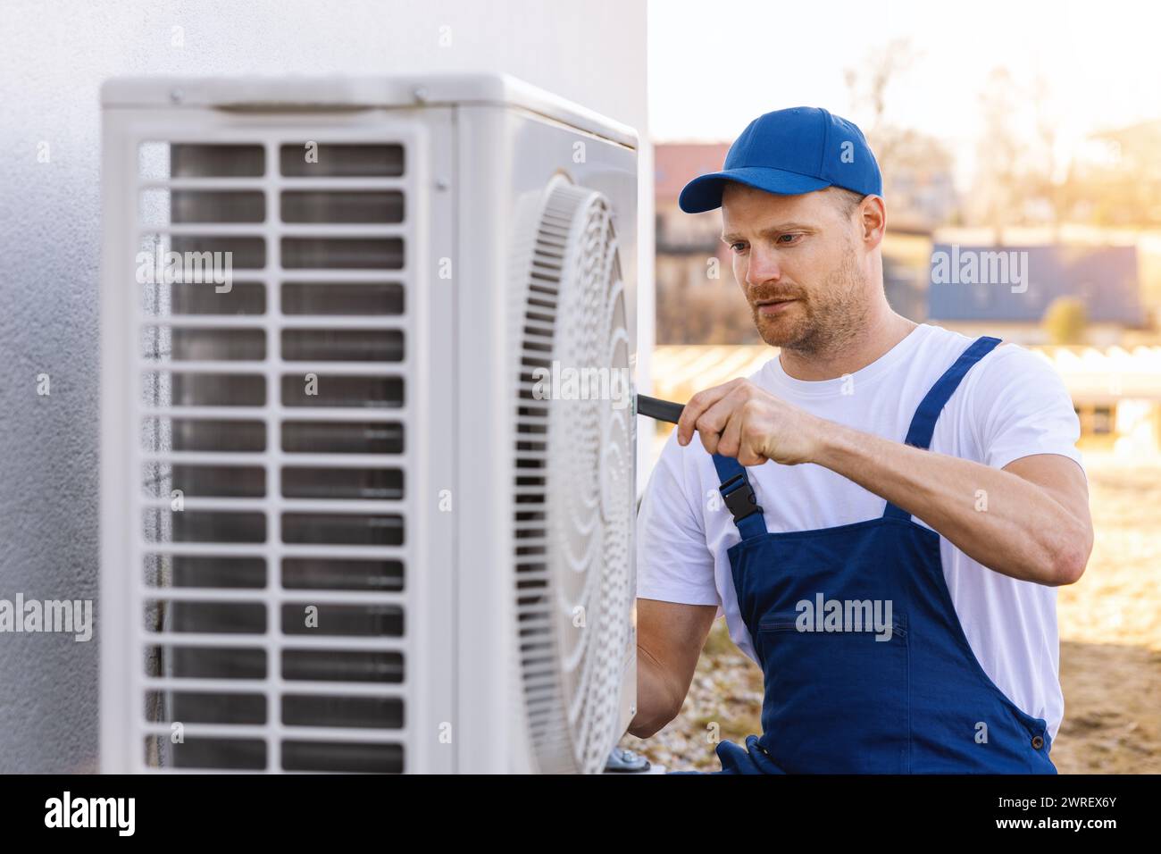 technician working on air conditioning or heat pump outdoor unit. HVAC service, maintenance and repair Stock Photo