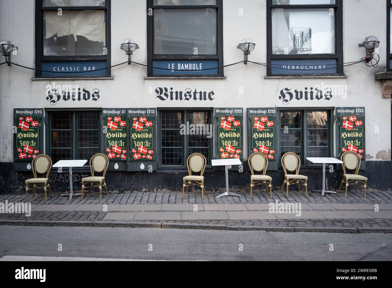 Hviids Vinstue, a popular 300 year old  pub at Kongens Nytorv in Copenhagen, Denmark with Danish flags outside Stock Photo