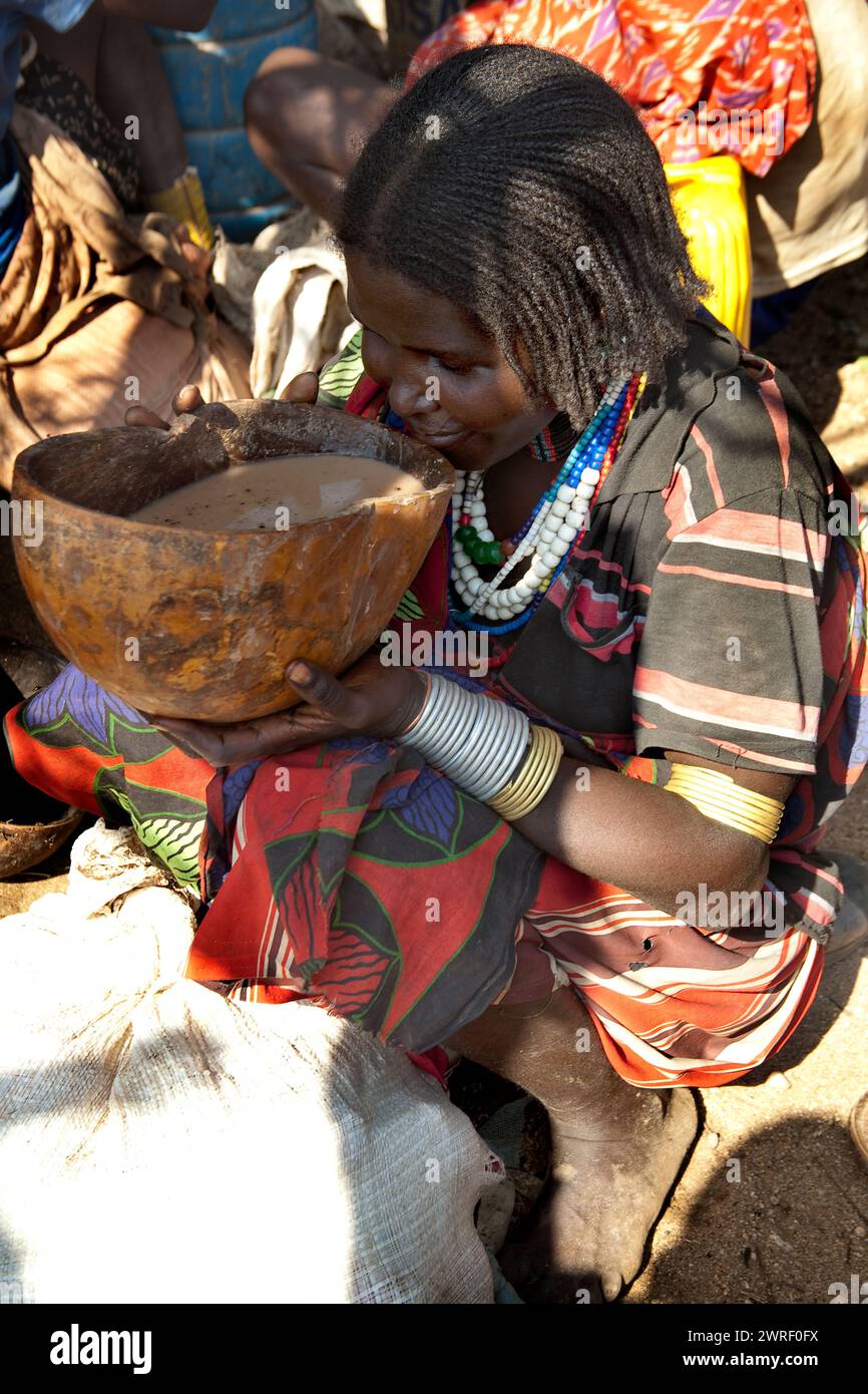 TURMI, OMO VALLEY, ETHIOPIA - NOVEMBER 19, 2011: Unidentified Hamar woman drinks self-made beer at village market. Weekly markets are important events Stock Photo