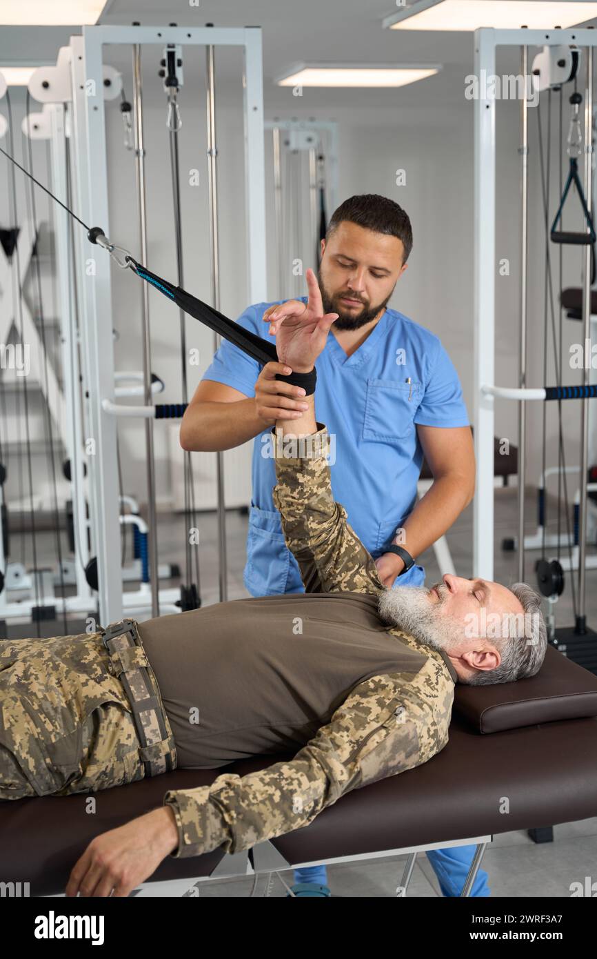 Experienced doctor helps patient perform exercises to stretch arm ...