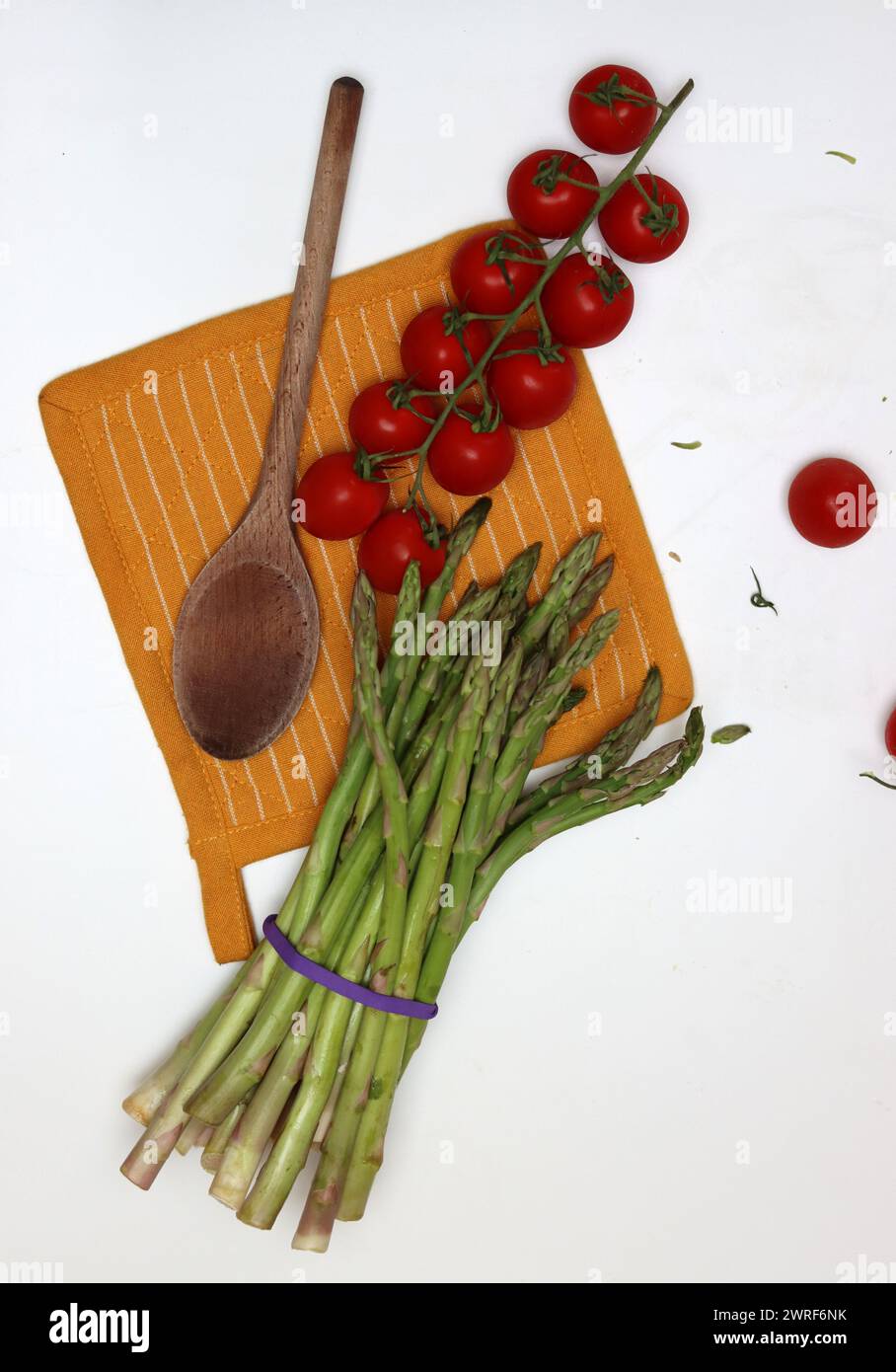 Fresh cherry tomatoes and green raw asparagus on white background with copy space. Eating fresh concept. Vegetarian meal ingredients. Stock Photo