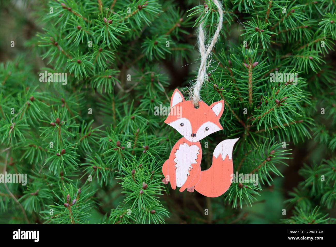 Wooden fox toy hanging on Christmas tree branch. Environmentally friendly Christmas decoration. Stock Photo