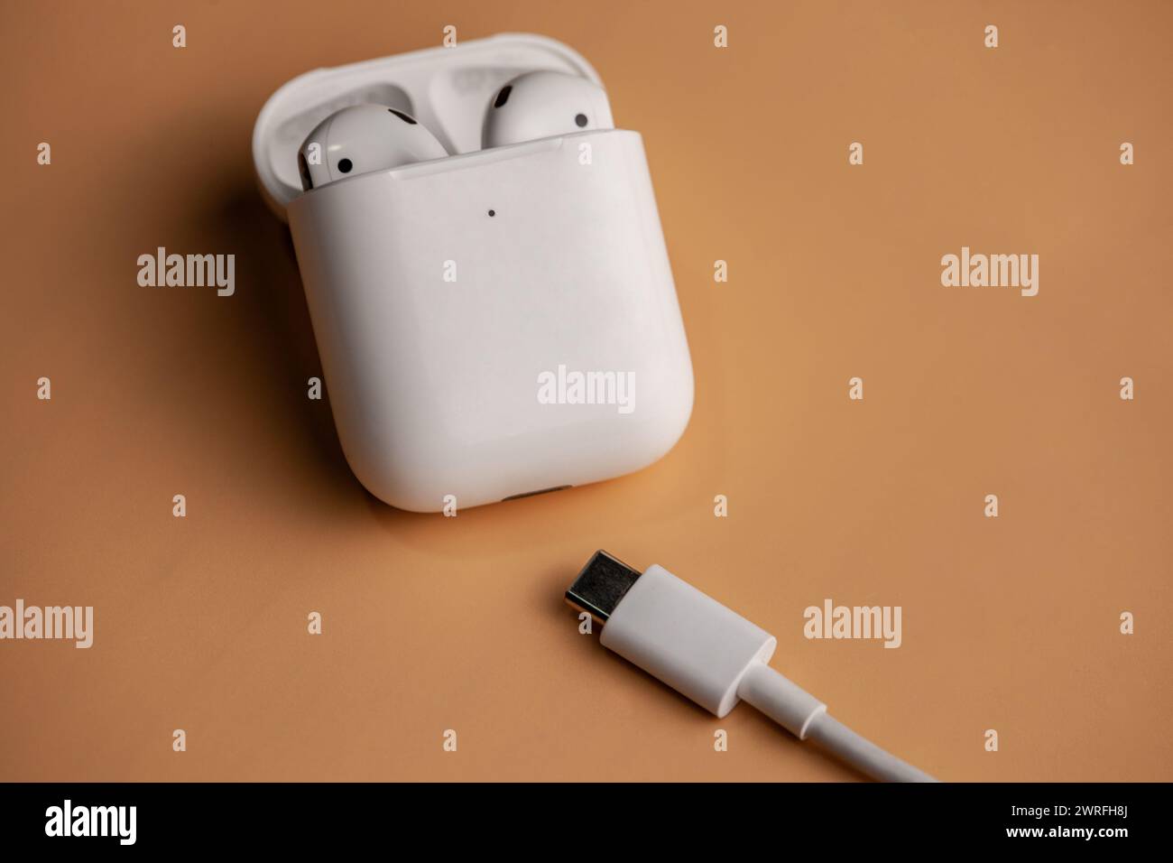 A picture of airpods on an orange background with the new type c charger.Hincesti,Moldova,11.09.2023 Stock Photo