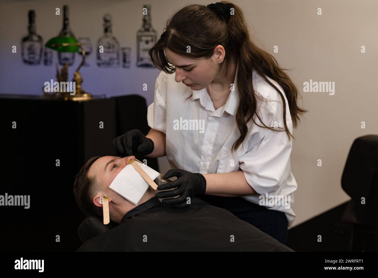 Hair removal procedure in a barbershop. Nose hair wax removal. Stock Photo