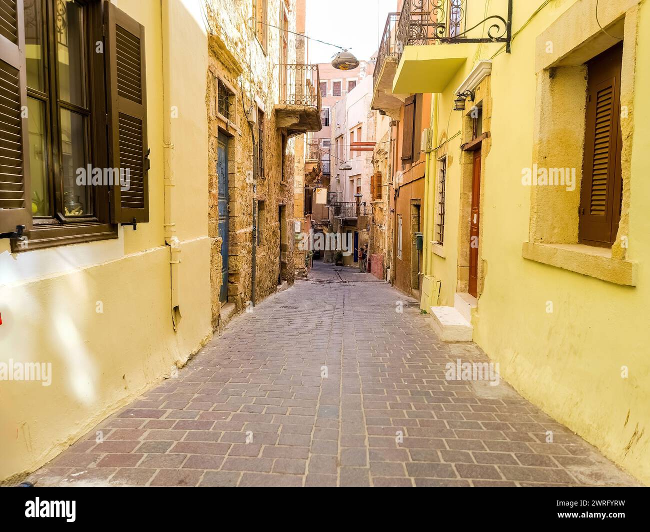 Chania Old Town, Crete island, destination Greece. Traditional narrow paved walkway between multicolor vintage building, summer sunny day. Stock Photo
