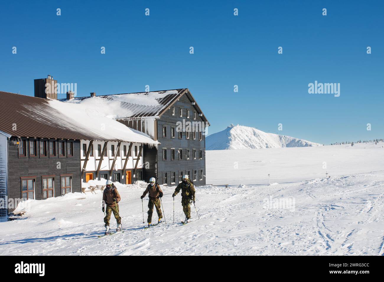 Three man on skies, ski touring in krkonose mountains, path in front of  Meadow Hut. Winter morning, on background  Snezka,  mountain on the border be Stock Photo