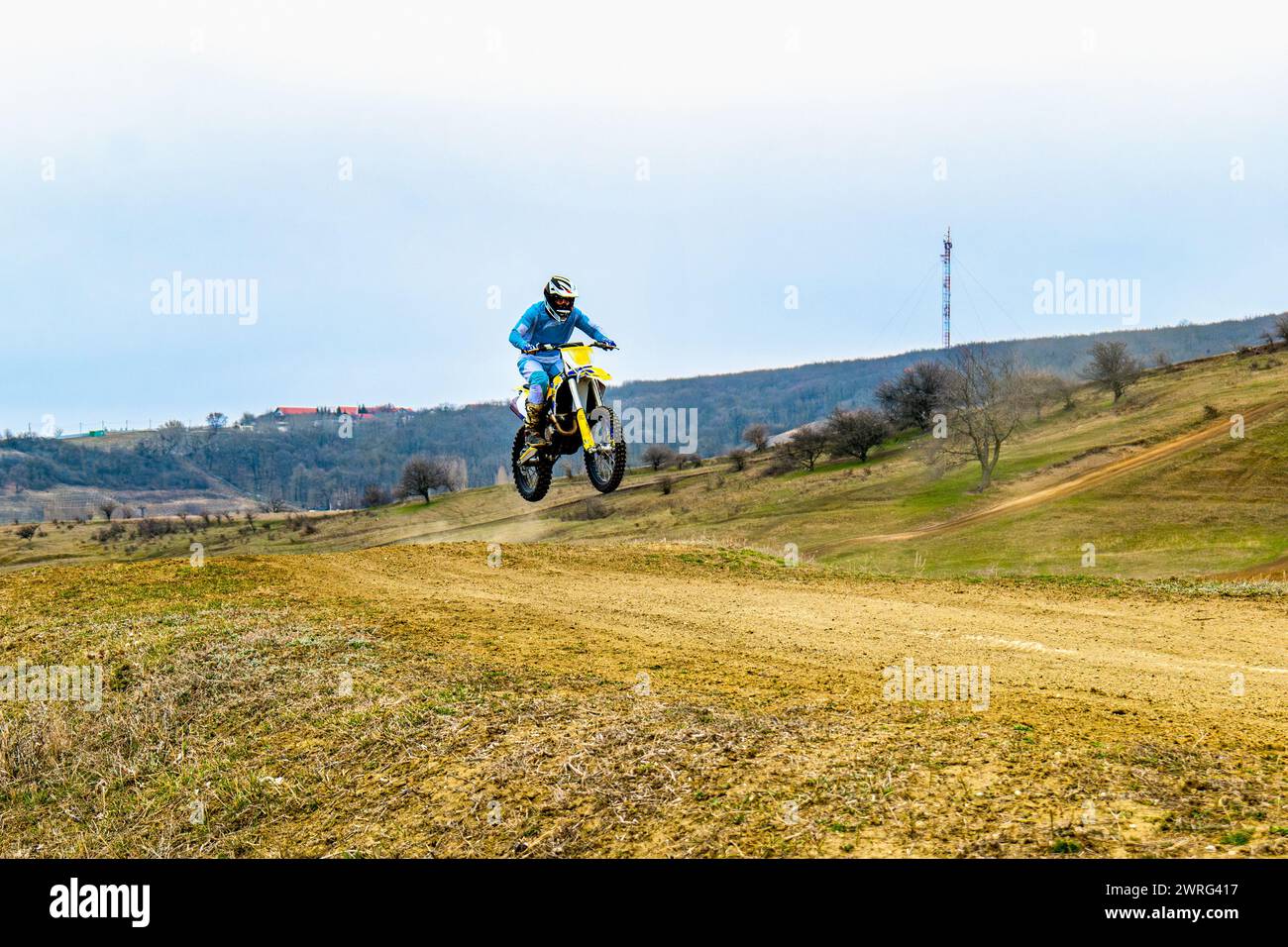 A person is tearing up a dirt road on a motocross bike, wearing a ...