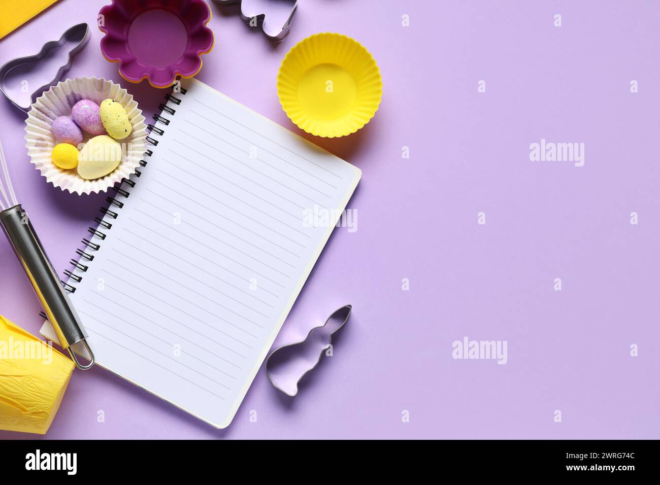 Blank notepad for recipes with Easter eggs and baking tools on lilac background Stock Photo