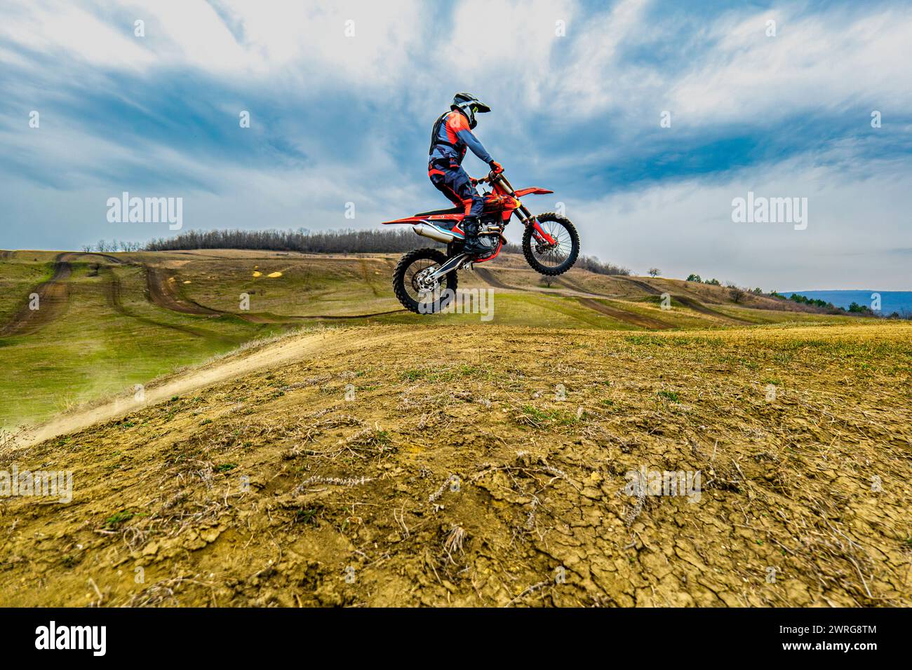 A man is cruising on a motorcycle through a dusty motocross track, with