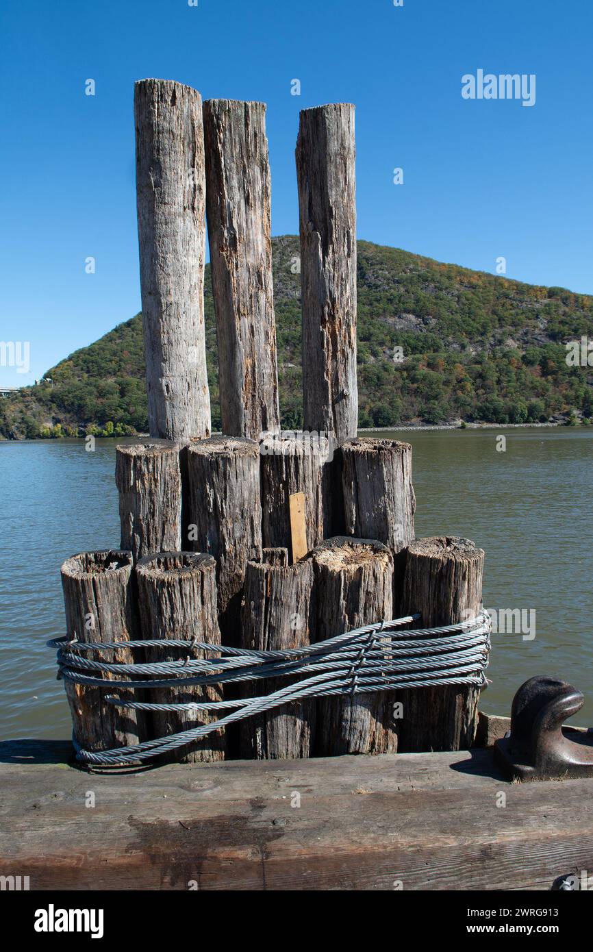Old mooring posts tied with steel wire on a river pier against a picturesque mountain Stock Photo