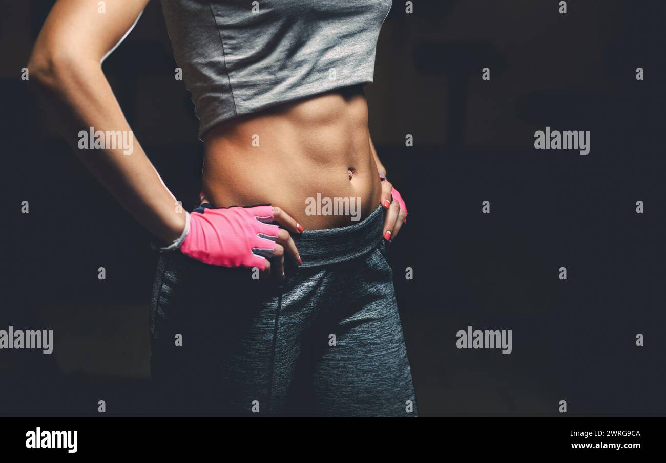 Thin, bodybuilder girl with a pumped up press on her stomach while training in the gym. Sports concept, fat burning and healthy lifestyle. Stock Photo
