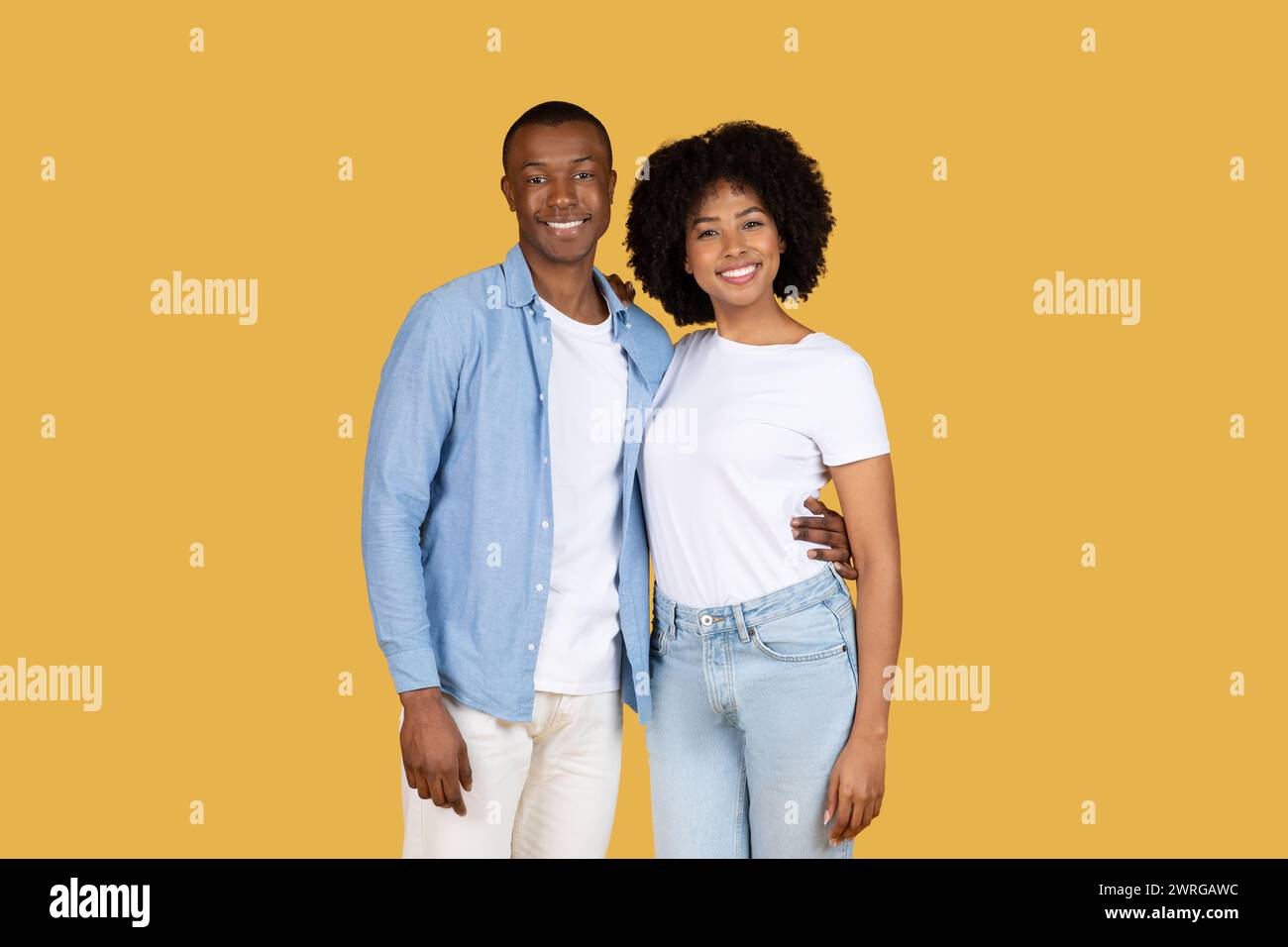 A cheerful young African American couple posing with bright smiles ...
