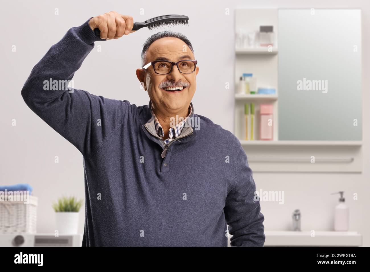 Mature man holding a hair brush in a bathroom Stock Photo