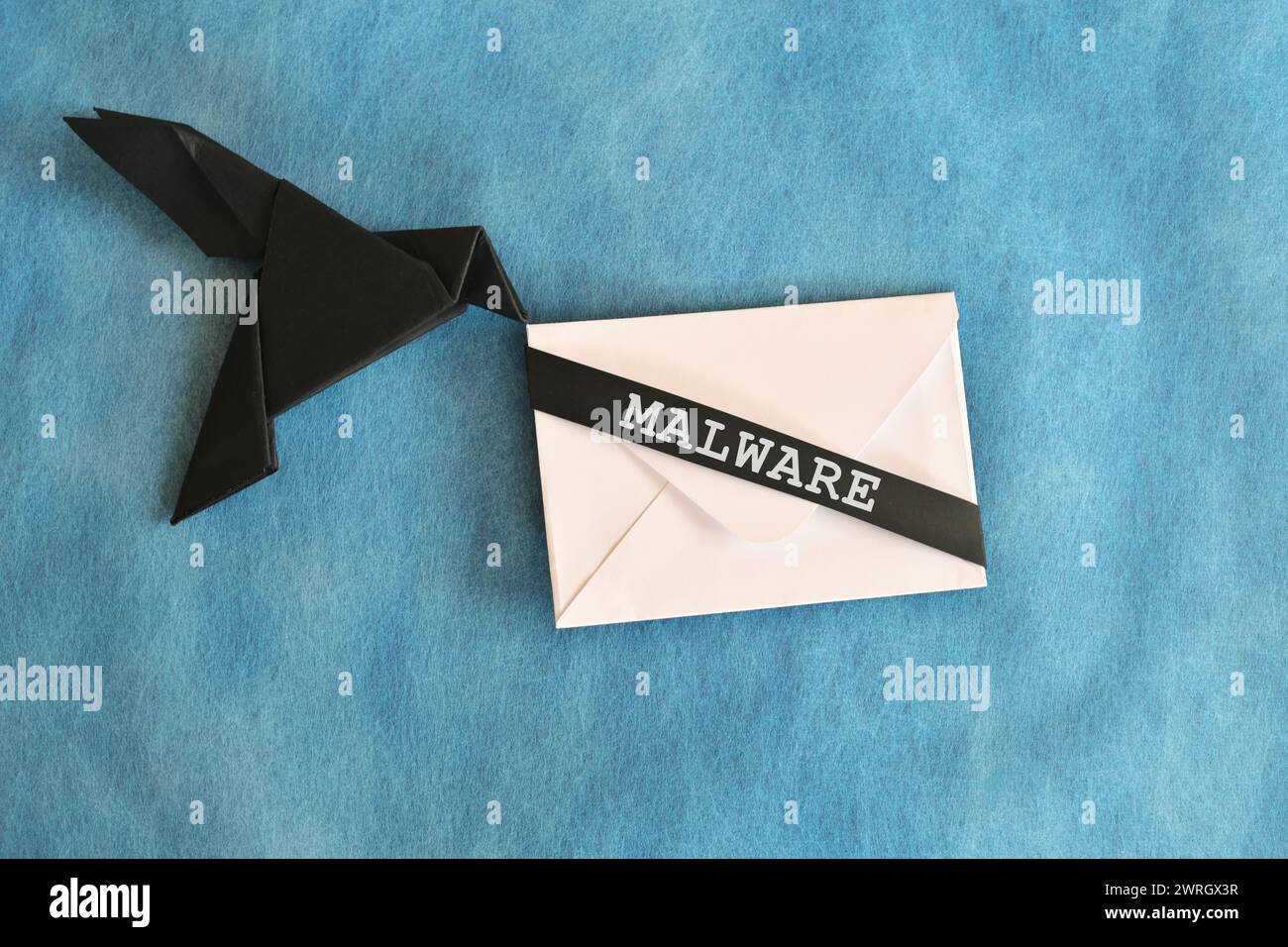 Black raven paper origami carrying white letter envelope with word Malware. Receiving malware attack email concept. Stock Photo