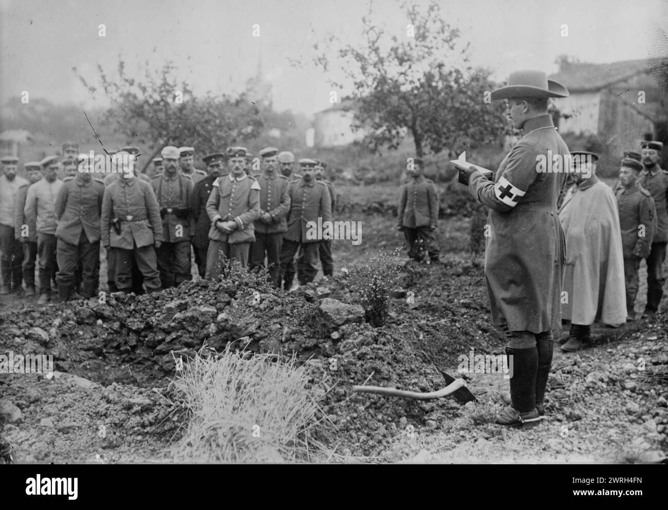 German Field chaplain burying French Officer who died in hospital, 1914. German chaplain standing next to a grave with other men, during World War I. Stock Photo