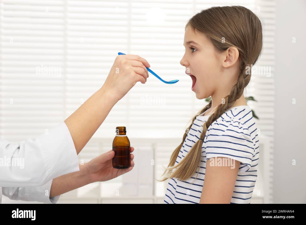 Doctor giving cough syrup to girl in clinic Stock Photo