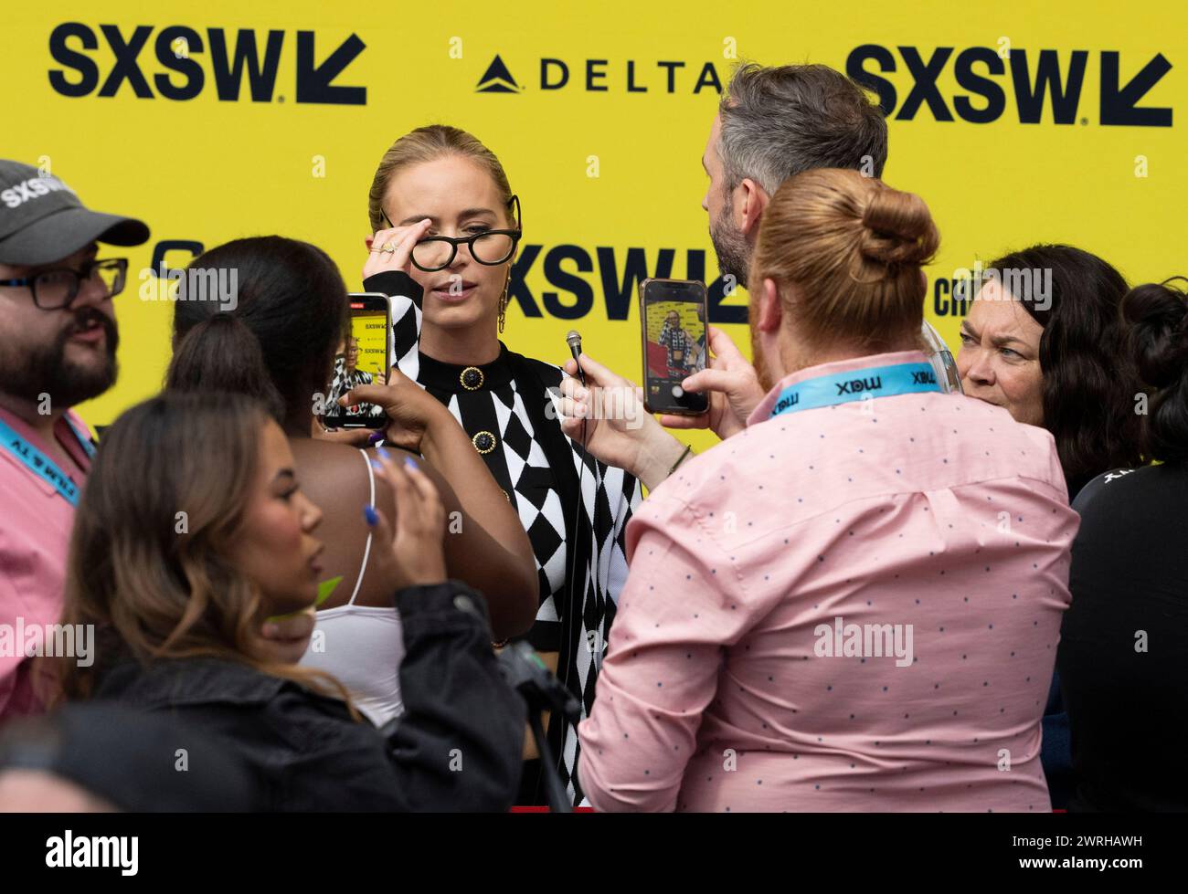 Actress EMILY BLUNT, who plays Jody Moreno in the new movie "The Fall Guy," adjust some glasses handed to her as she walks the red carpet outside the Paramount Theater in downtown Austin at the movie's world premiere during the South by Southwest (SXSW) film festival on March 12, 2024. Credit: Bob Daemmrich/Alamy Live News Stock Photo