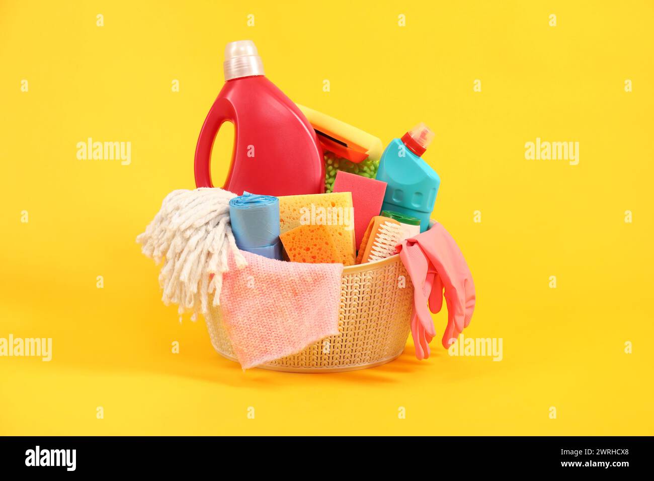 Different cleaning products in basket on yellow background Stock Photo