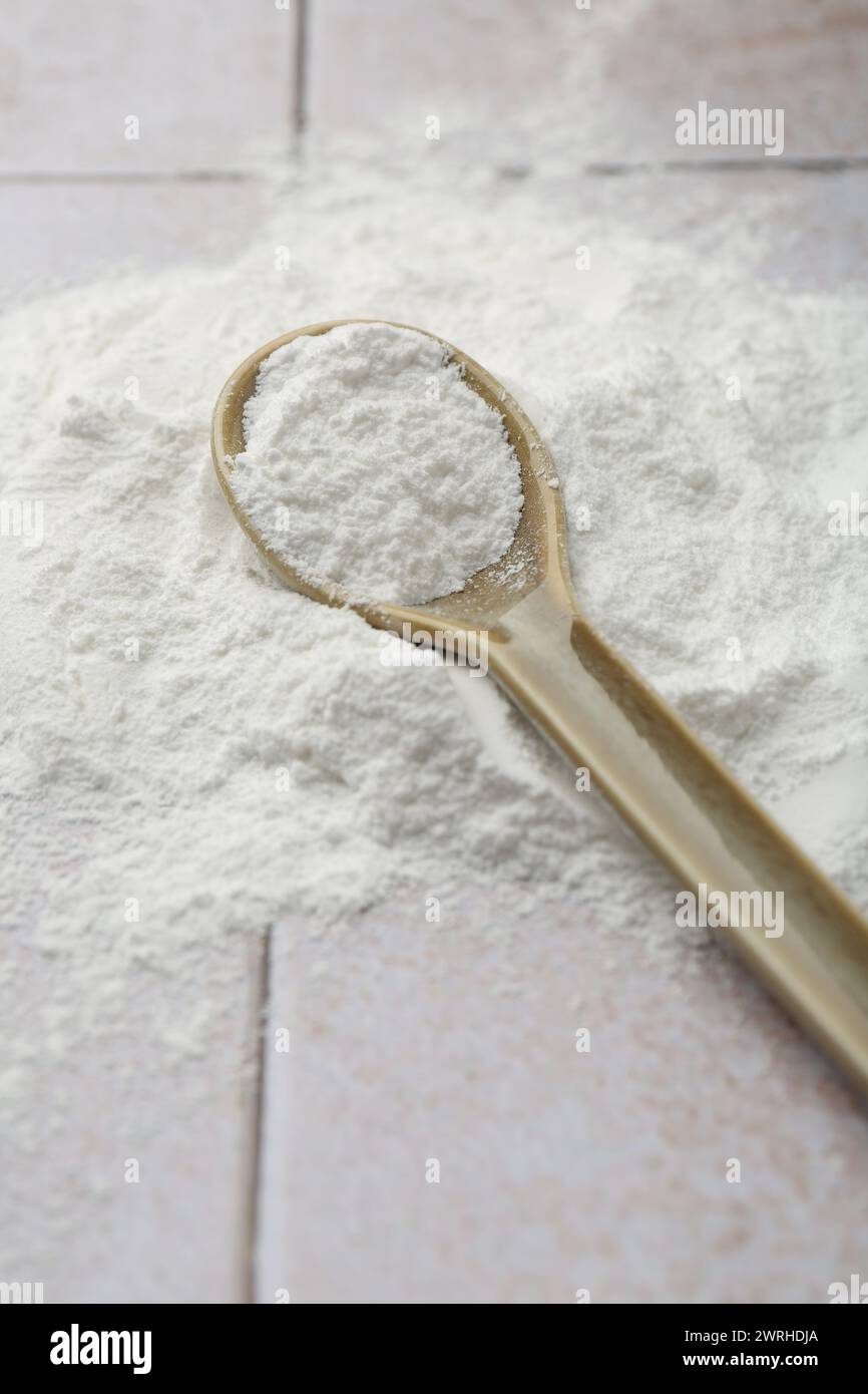 Pile of baking powder and spoon on light tiled table, closeup Stock ...