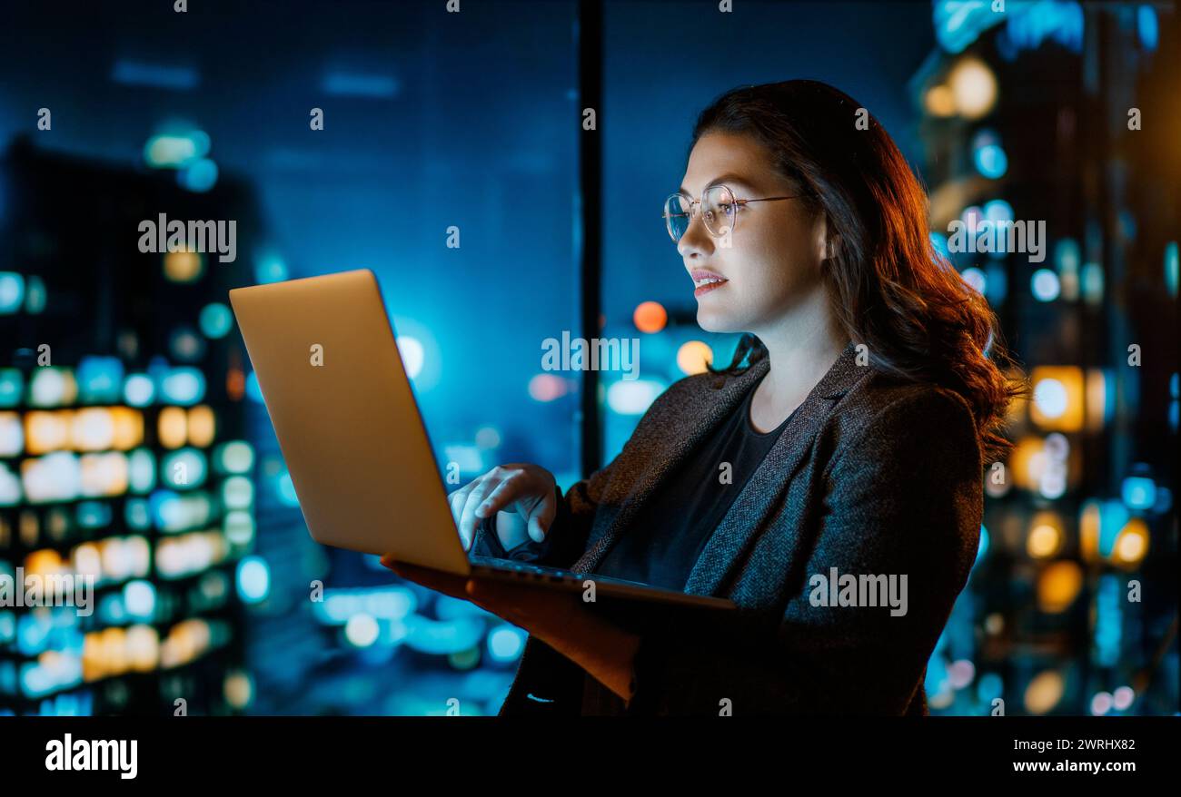 Young businesswoman standing near window with laptop. Stock Photo