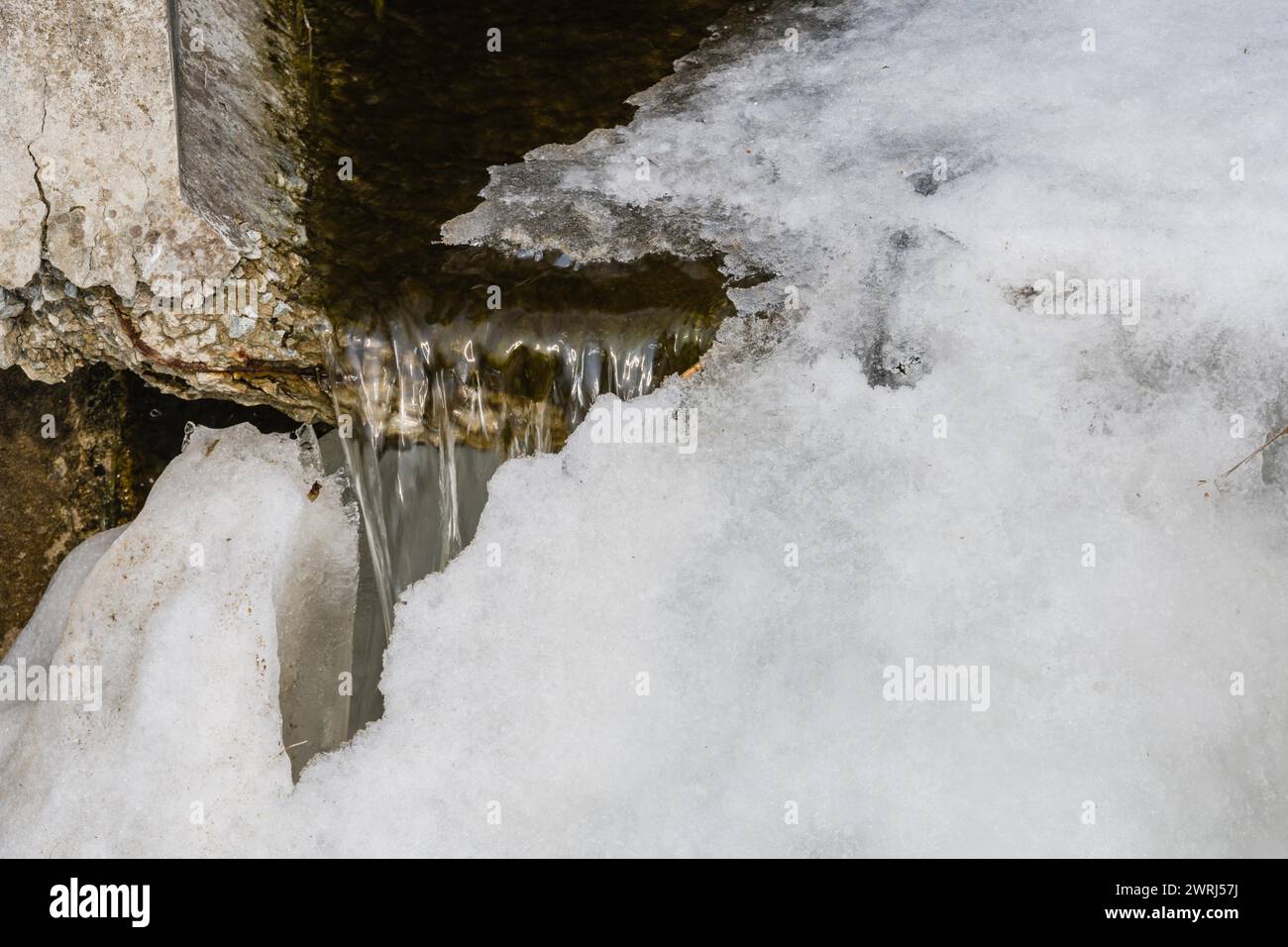 Extreme closeup of ice formation at mouth of concrete culvert of flowing water in Daejeon, South Korea Stock Photo