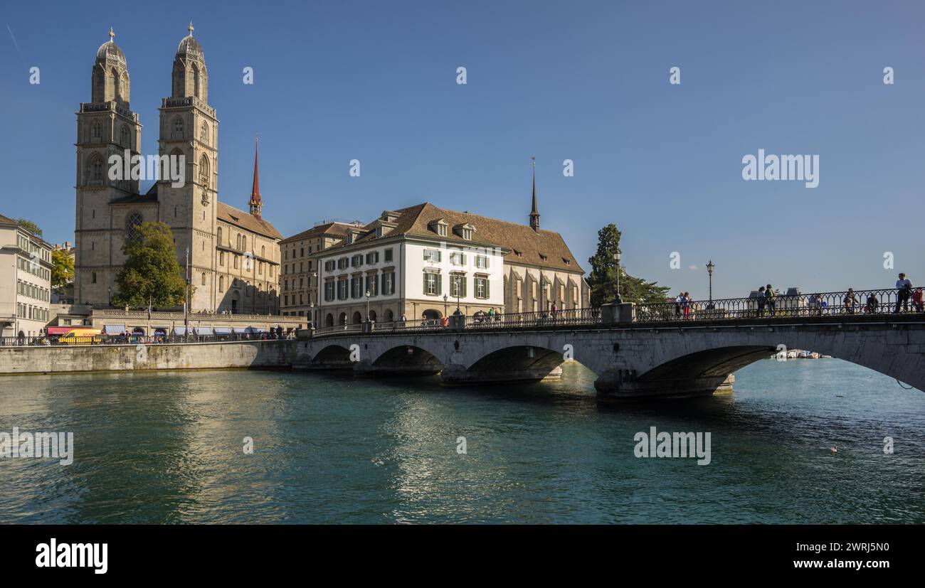 A bridge over a river with a view of a church and historic buildings under a clear blue sky Zurich Switzerland Stock Photo