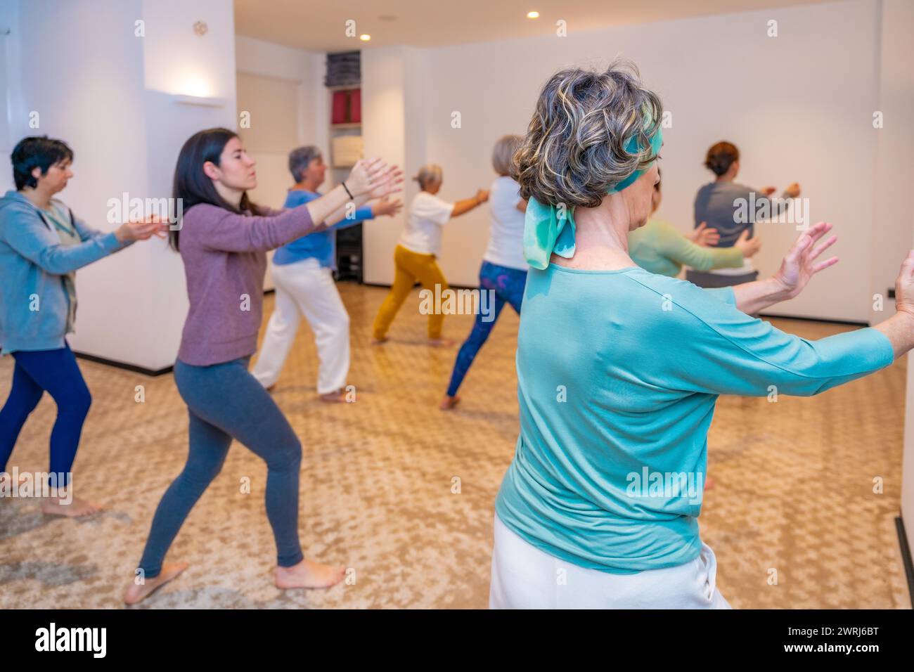 Group of women simulating waves in a choreographed Qi Gong exercise in a classroom Stock Photo