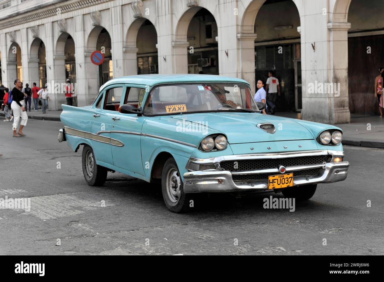 Light blue vintage car as a taxi on a busy street with passers-by in the background, Havana, Cuba, Central America Stock Photo