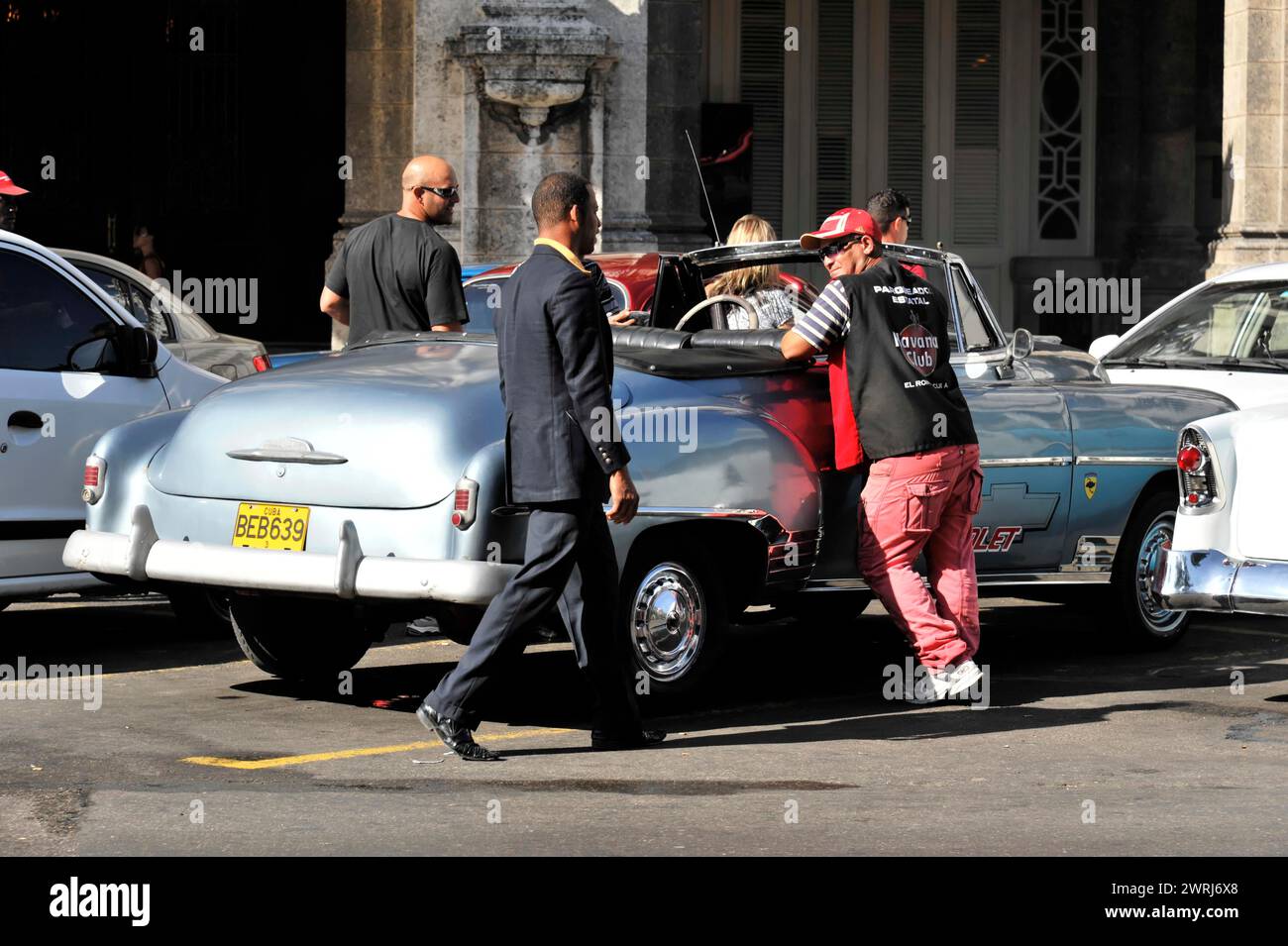 People helping elderly person into a taxi on a busy city street, Havana, Cuba, Central America Stock Photo