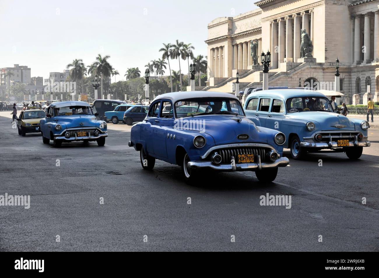 Row of vintage cars driving on a wide city street, Havana, Cuba, Central America Stock Photo