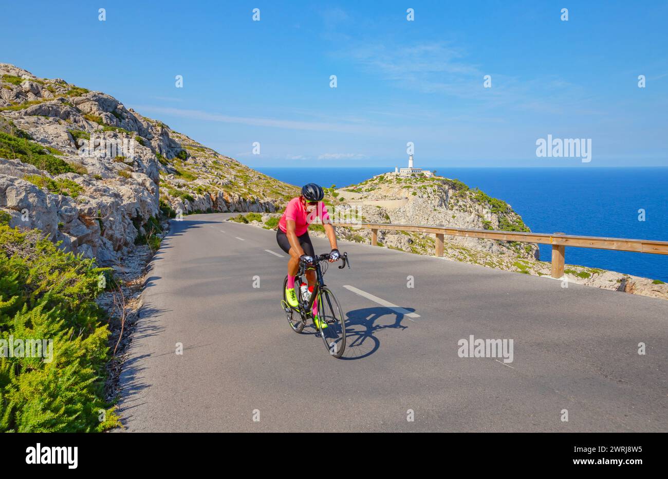 Cyclist going up steep mountain road near Cap de Formentor, Mallorca, Balearic Islands, Spain Stock Photo
