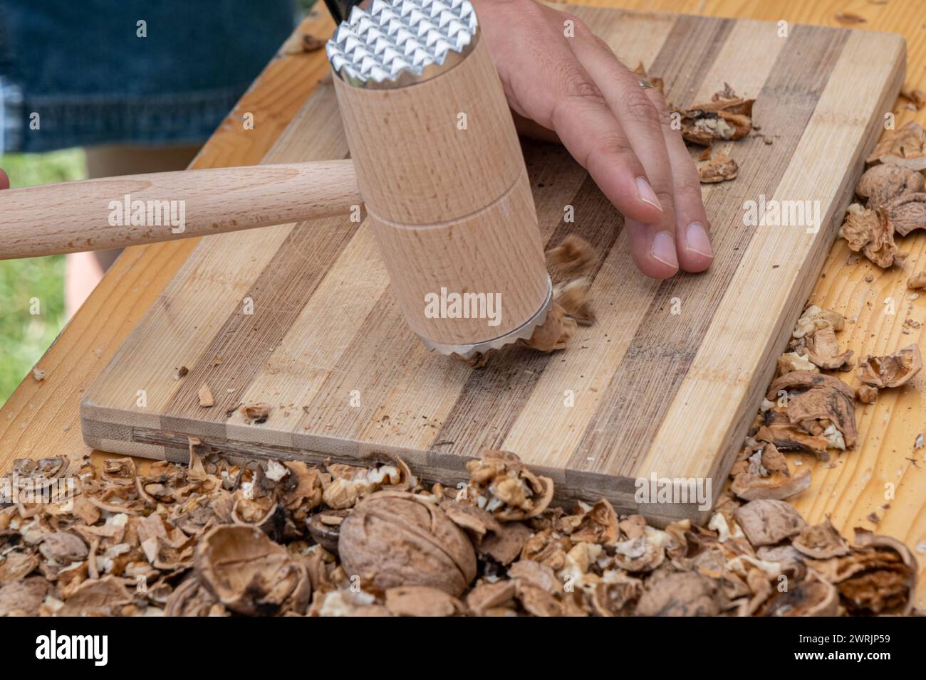 Man cracking walnuts with hammer at table, closeup Stock Photo