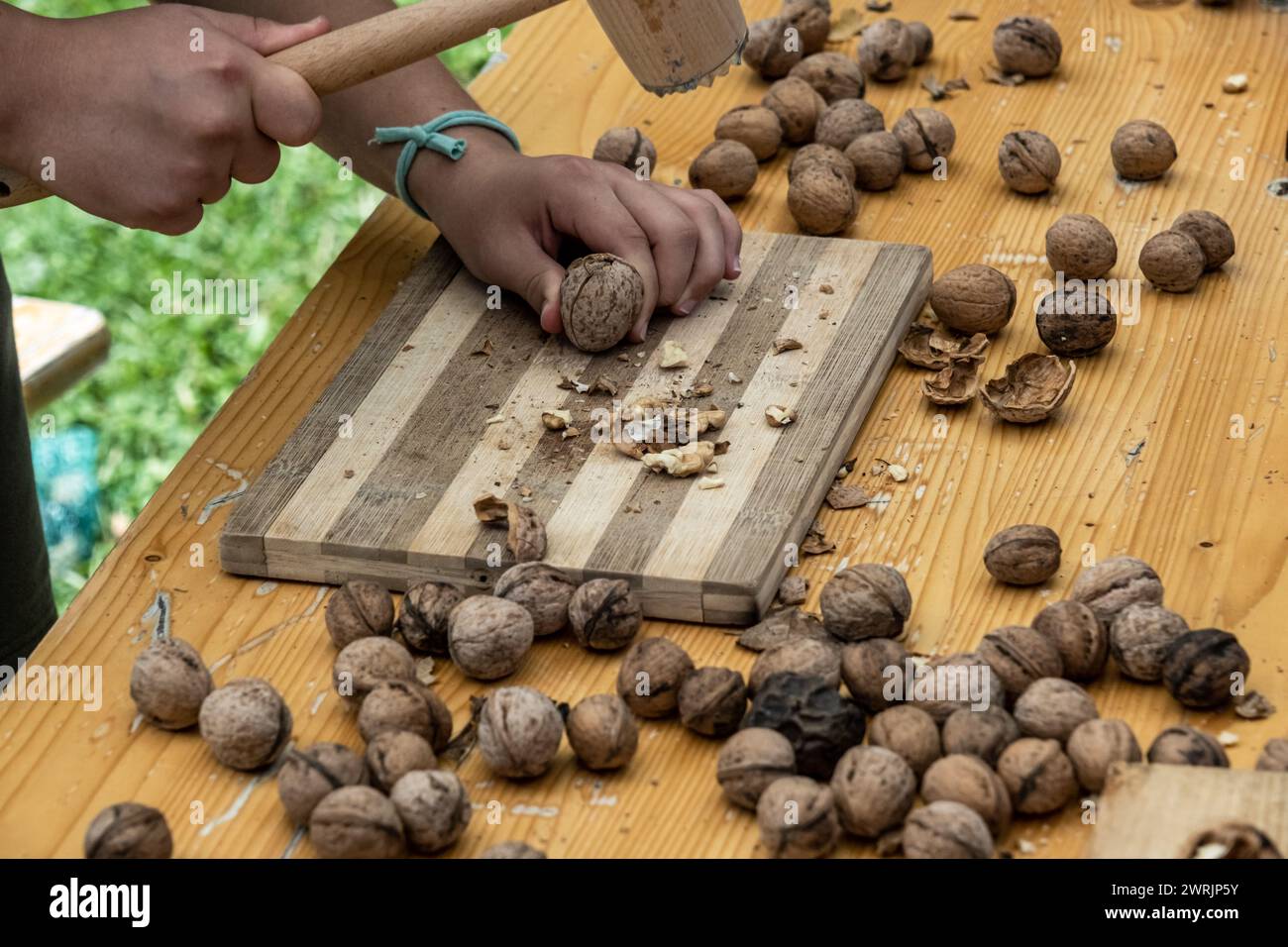 Man cracking walnuts with hammer at table, closeup Stock Photo