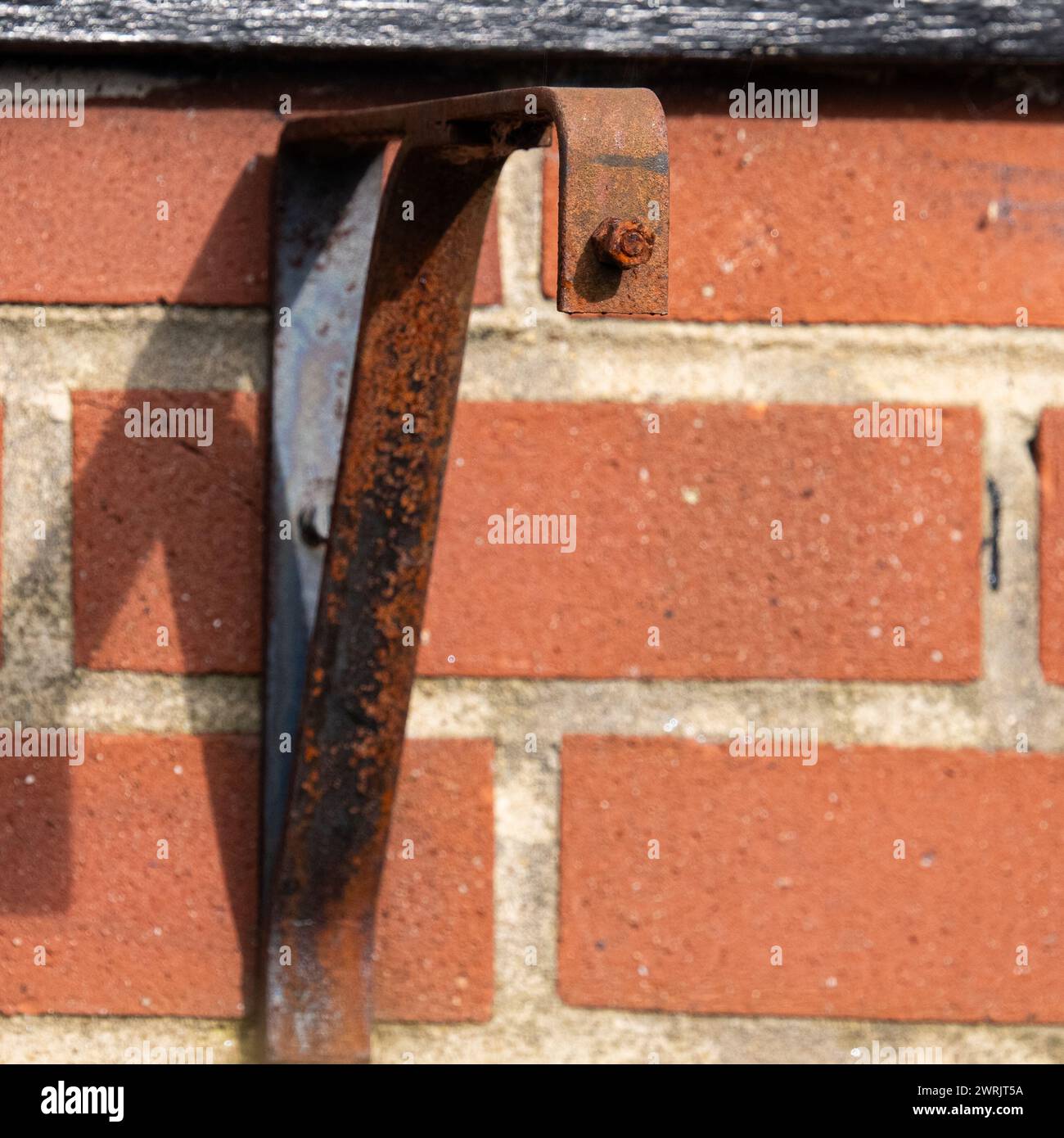Old rusty wall bracket on a red brick textured wall. Stock Photo