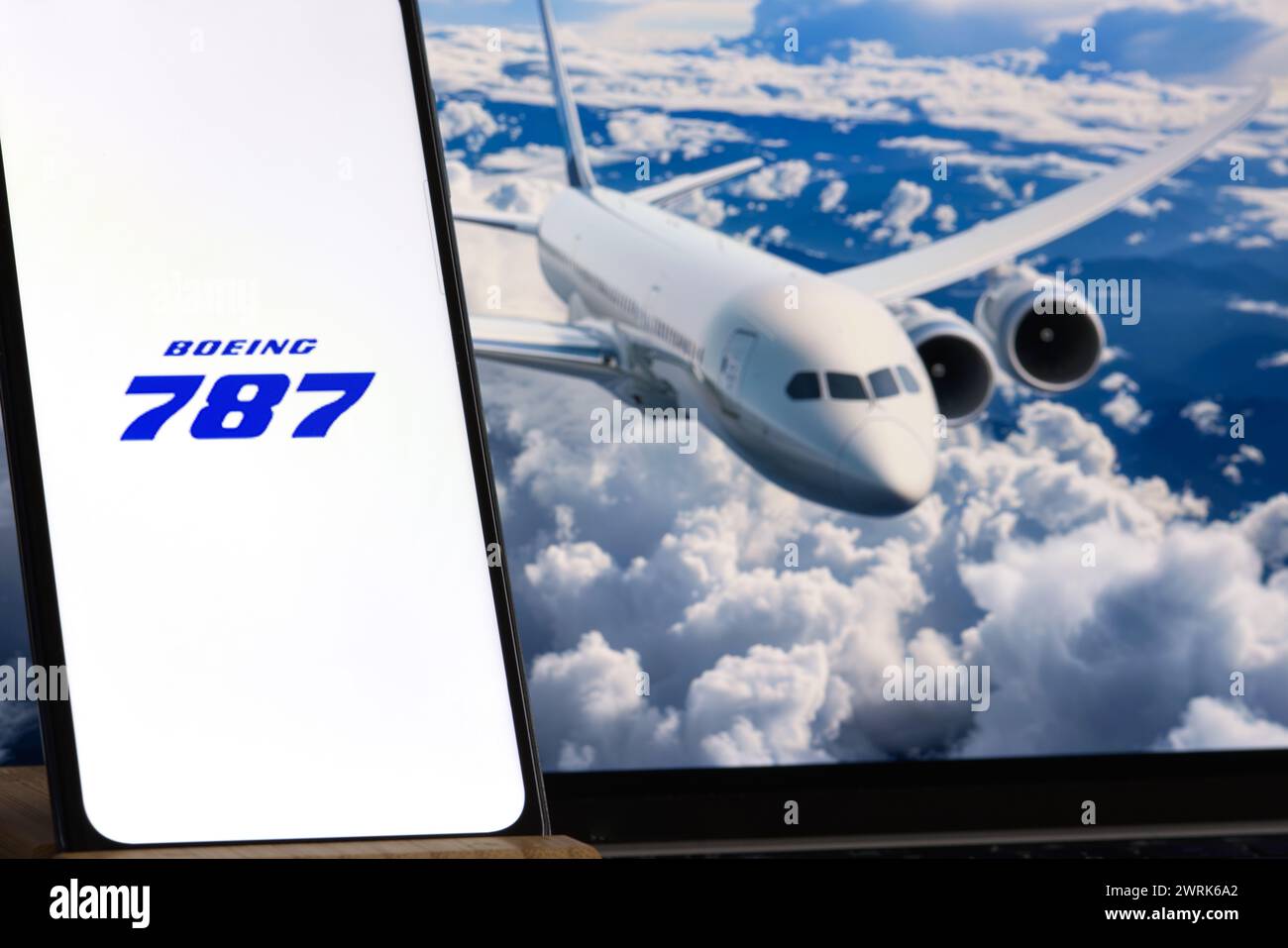 Boeing 787 logo is sharp in the foreground, while flying airplane is blurred in the background. Stock Photo