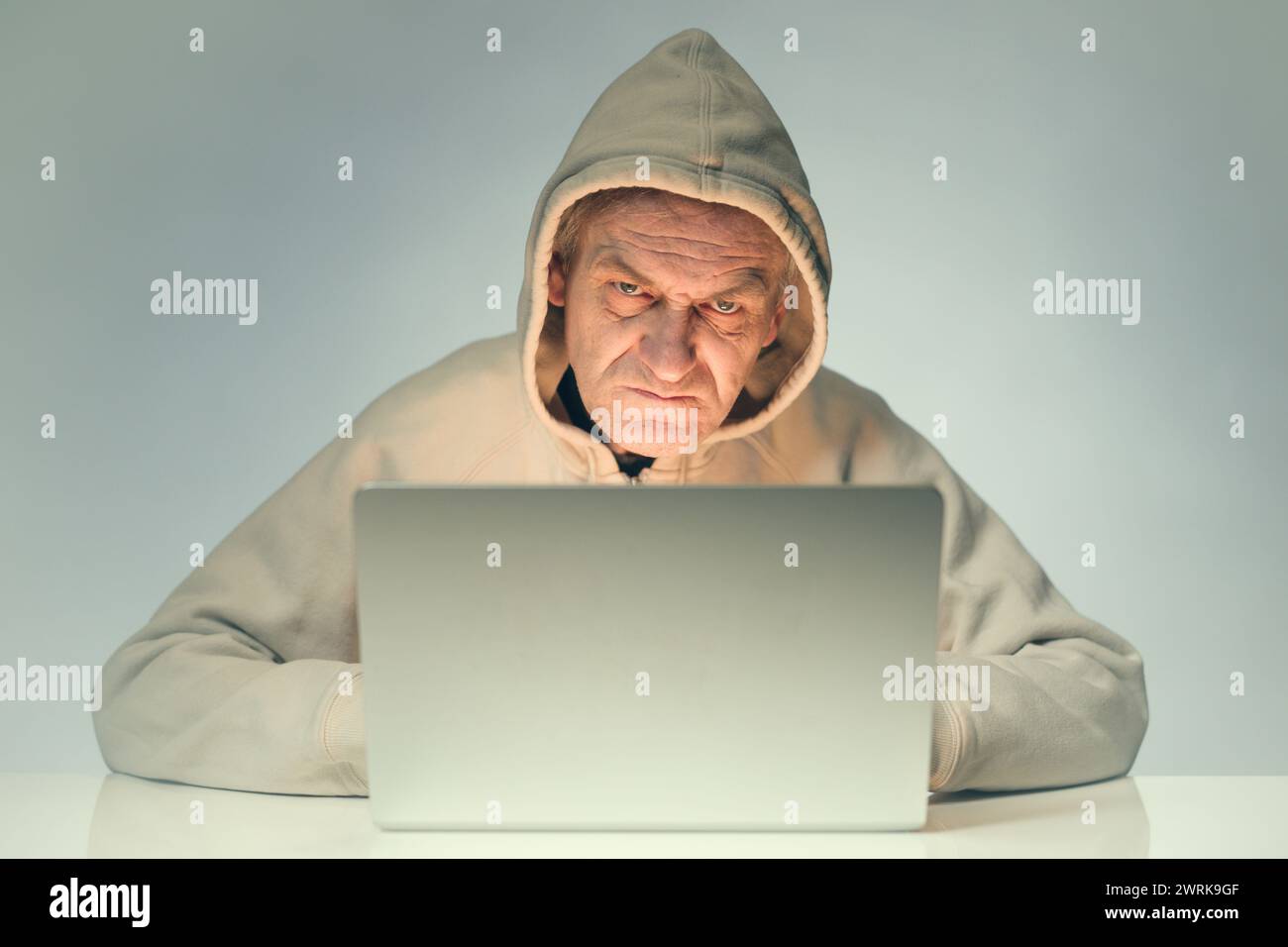 Older criminal man using computer for remote money robbery Stock Photo