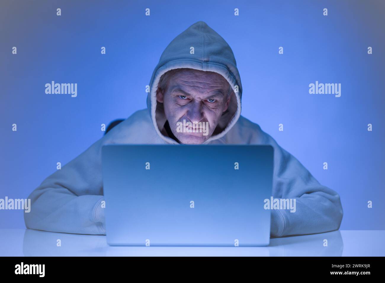 Older criminal man using computer for remote money robbery Stock Photo