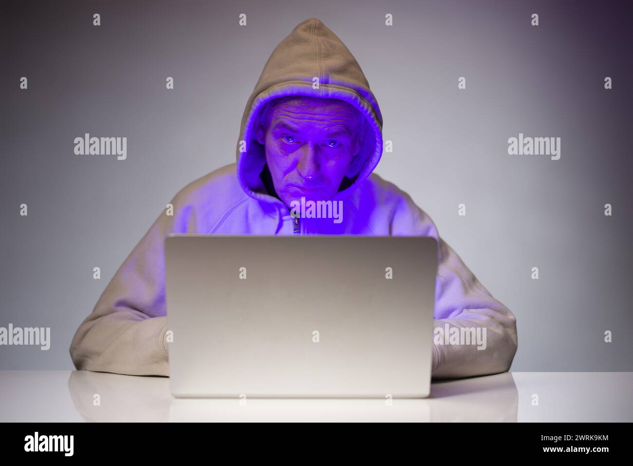 Older criminal man using computer for remote money robbery Stock Photo