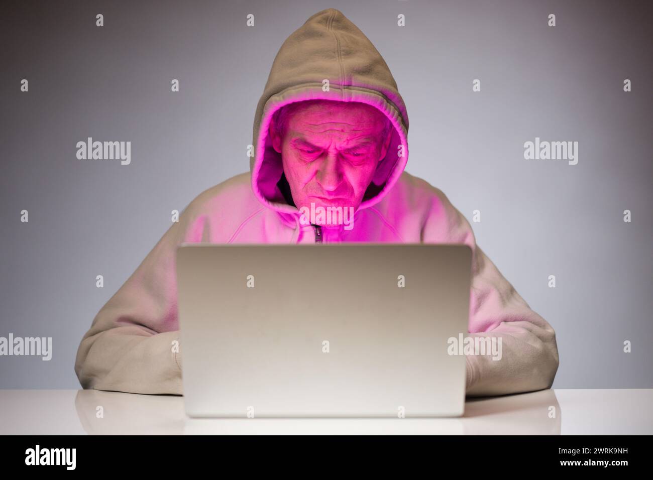 Older criminal man using computer for remote money robbery Stock Photo