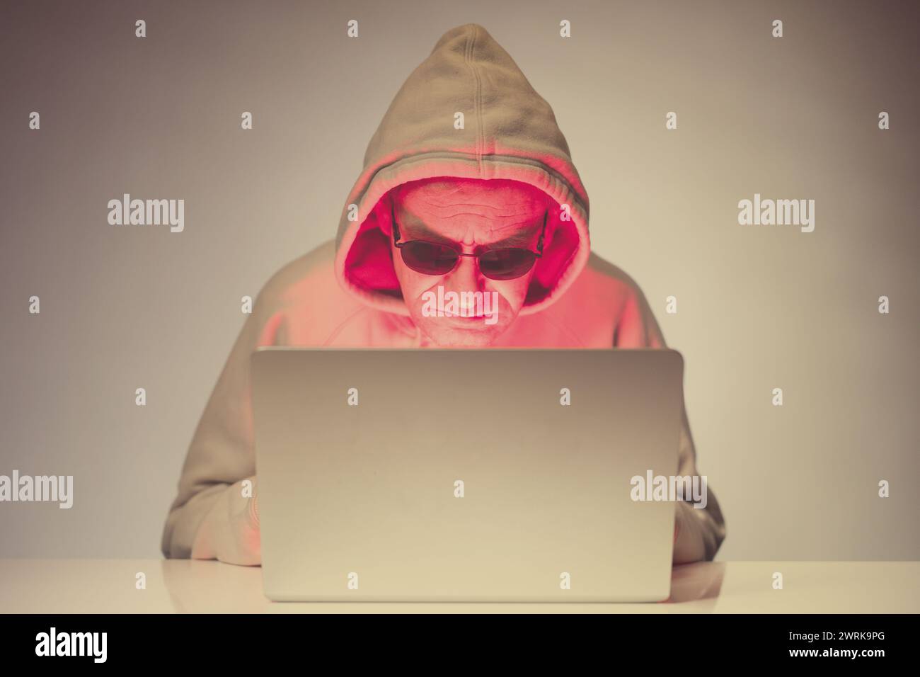 Older criminal man using computer for remote money robbery Stock Photo