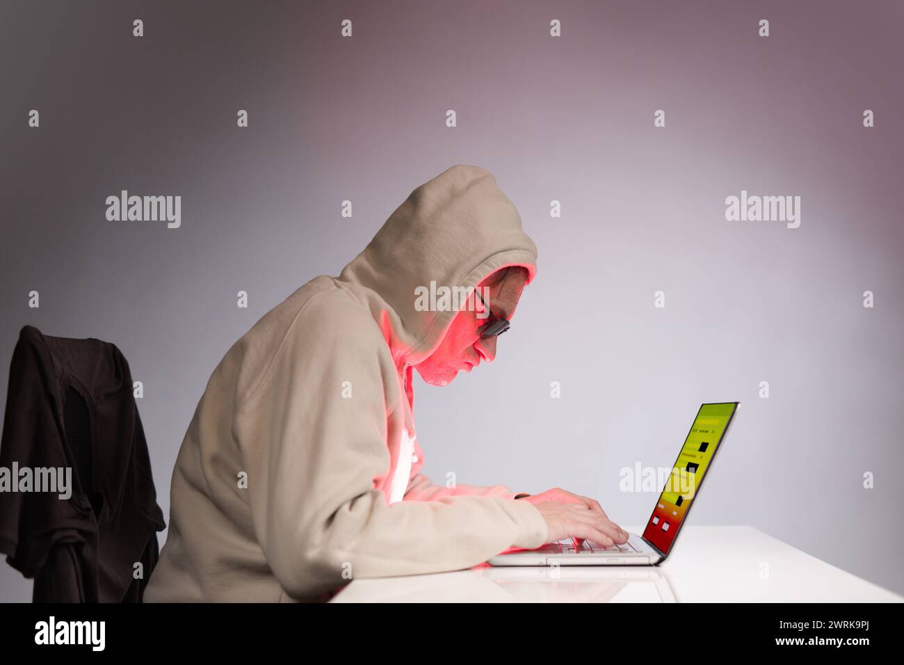Older criminal man using computer for remote money robbery Stock Photo